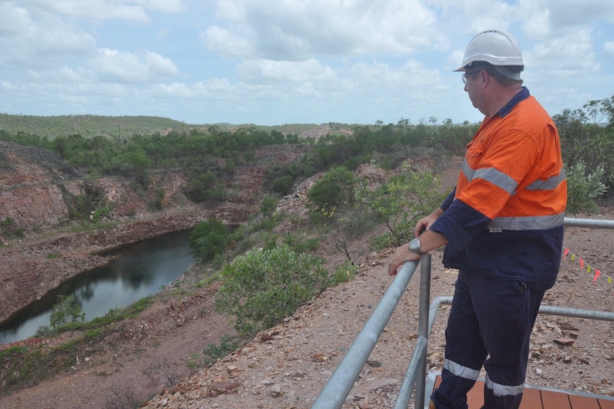 Mark Edwards photographed at the Unions Reef mine site. He is stranding behind a metal railing and looking at the site.
