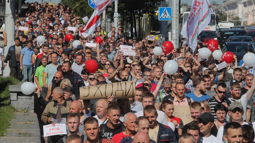 A large crowd of adults march while carrying handmade signs reading "Go away" in Cyrillic.