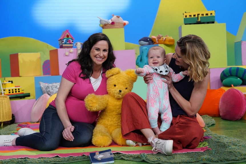 Presenter Emma Palmer with a small baby and her mother on the set of Play School.