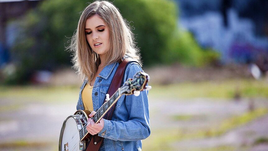 Country singer Taylor Pfeiffer holding a banjo