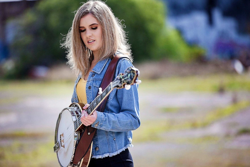 Country singer Taylor Pfeiffer holding a banjo