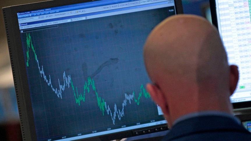 A trader watches a falling graph on the floor of the New York Stock Exchange