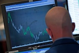 A trader watches a falling graph on the floor of the New York Stock Exchange