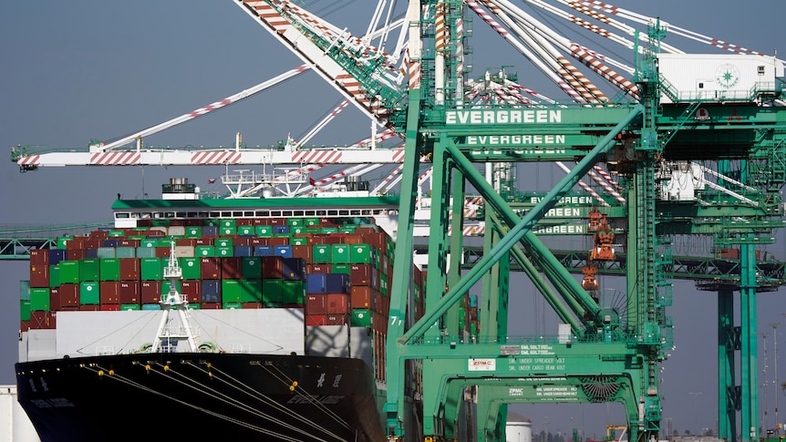 A cargo ship stacked with shipping containers is docked at the Port.