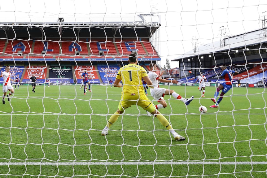 A picture from behind the net shows a striker swivel and strike the ball into the net.
