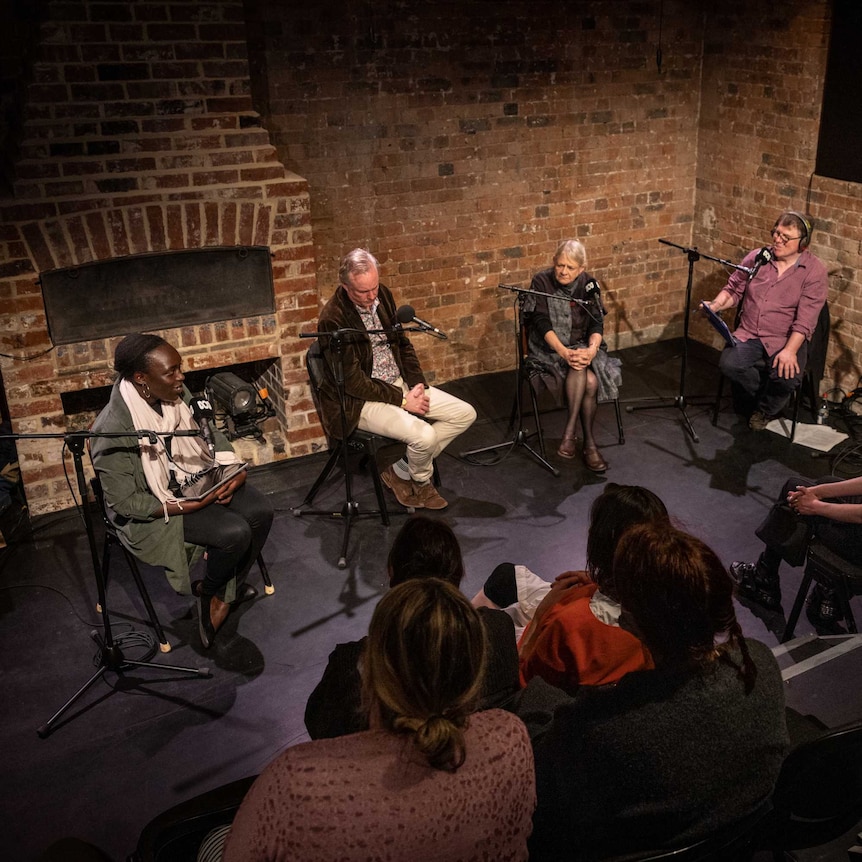 From left to right: Kush Kuiy, Julian Meyrick, Liz Jones and Michael Cathcart sit at microphones in the brick La Mama theatre.
