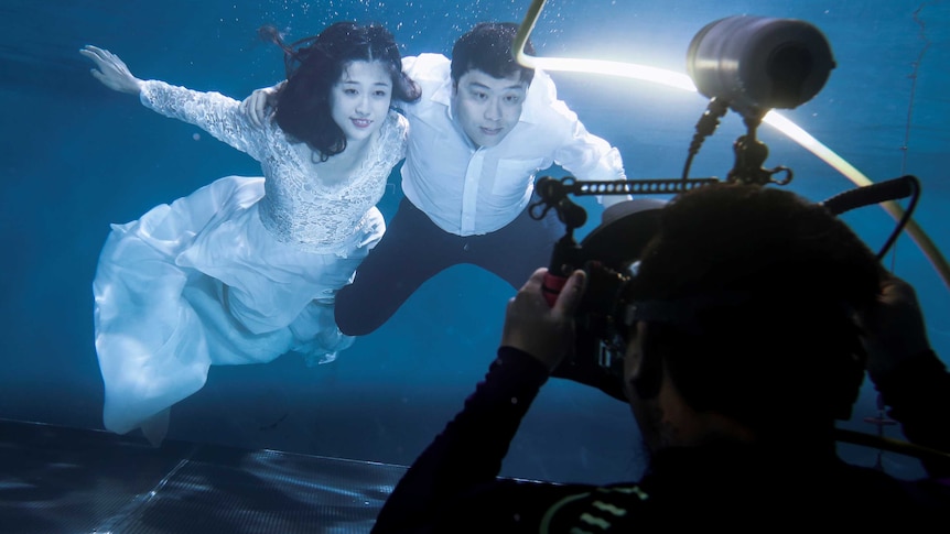 A couple has their wedding photograph taken underwater.