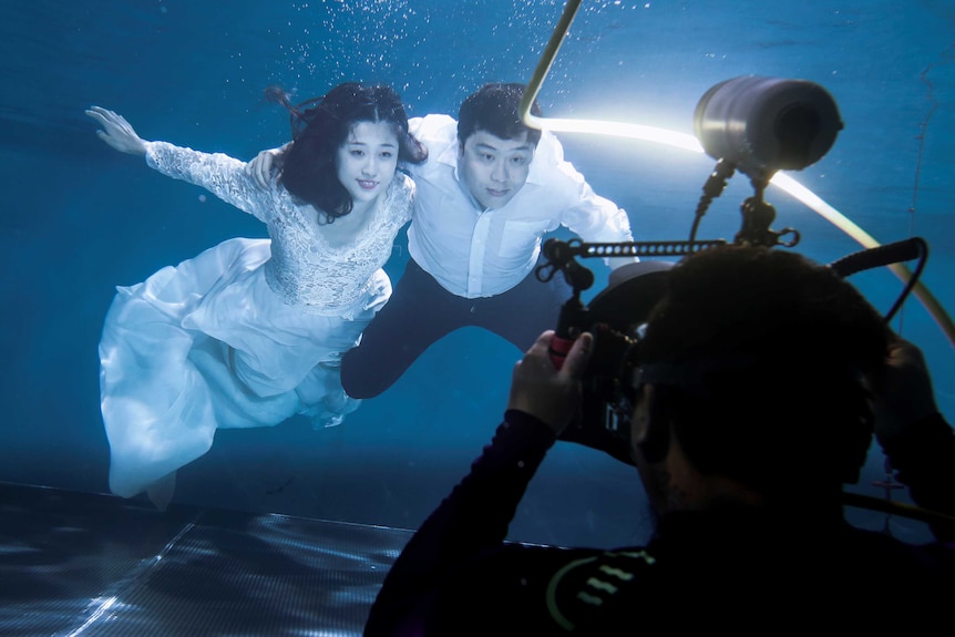 A couple has their wedding photograph taken underwater.