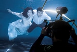 A couple has their wedding photograph taken underwater.