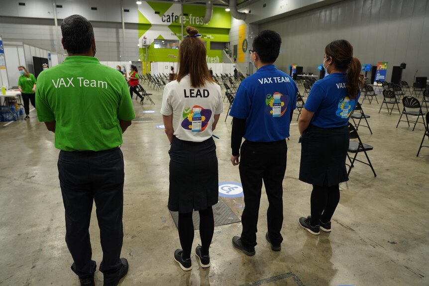 Four staff with t-shirts reading Vax Team stand in the exhibition hall.