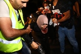 Men carry a woman in a hijab bleeding from her face