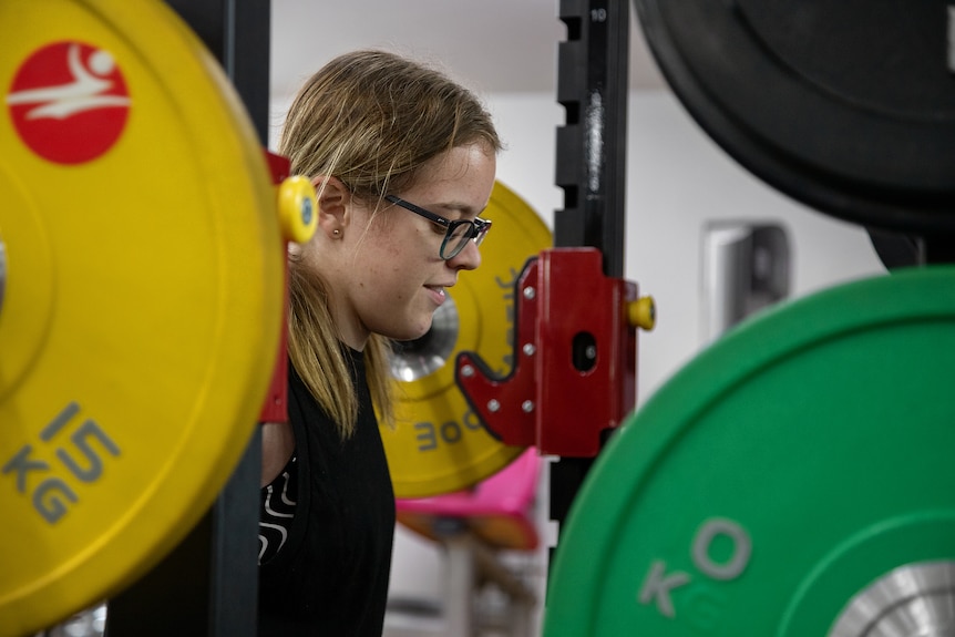 Julie Dickson looks ahead as she lifts a bar with 15 kilogram weights on either end.