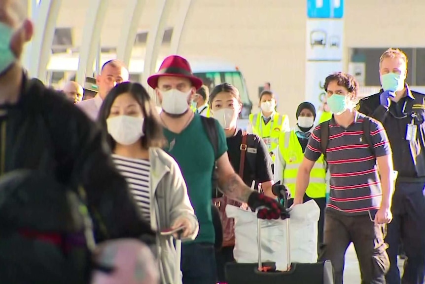 A line of passengers wearing masks.