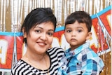 A woman wearing a striped shirt holding a male toddler