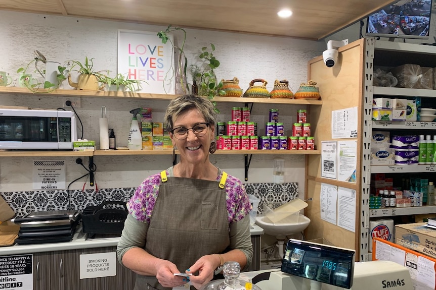 A lady in front of shelves at a cash register