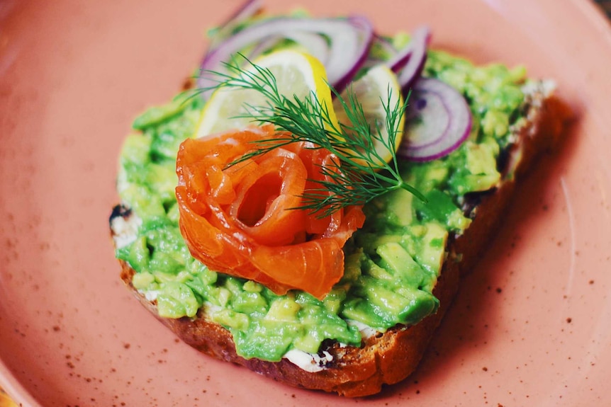 Smashed avocado on toast on a plate.