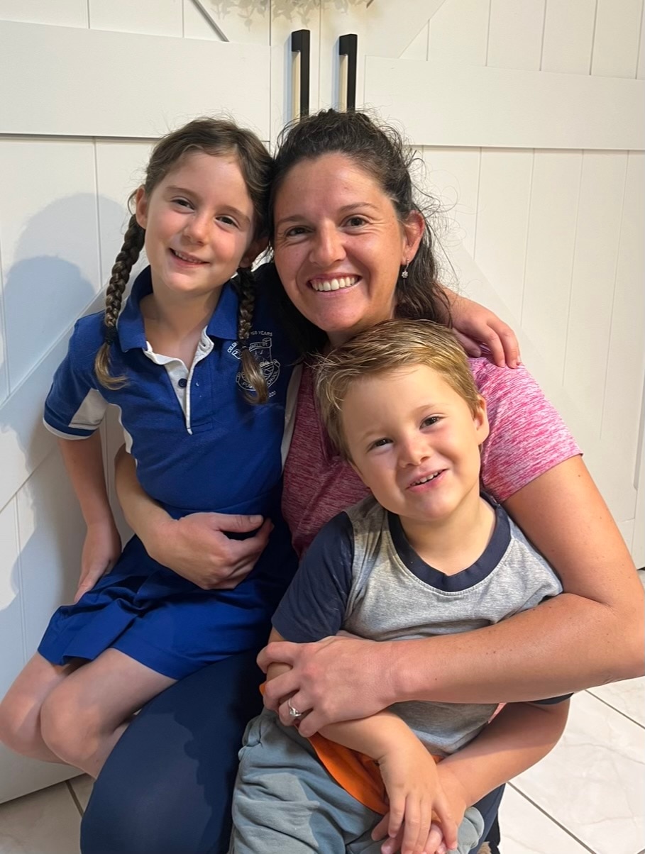 Brunette woman hugging her young son and daughter