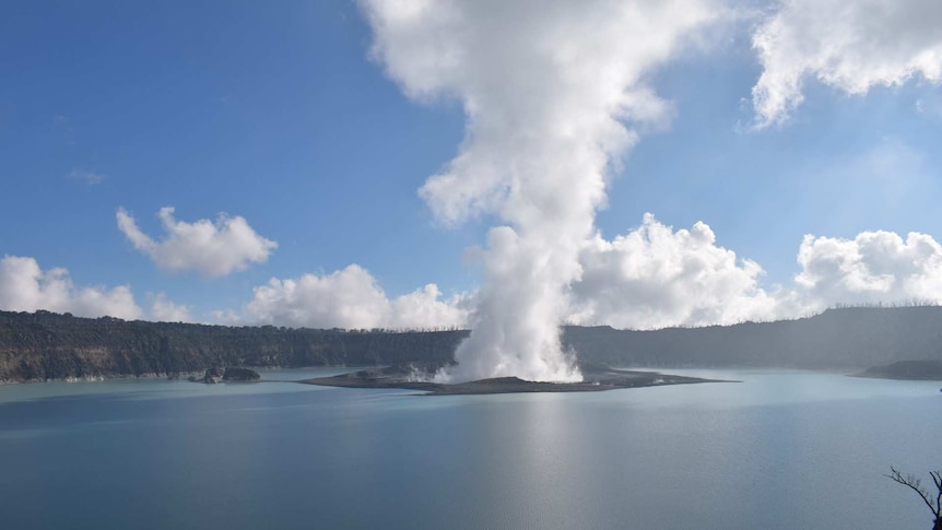 Smoke is seen coming out of Manaro volcano in the middle of a body of water.