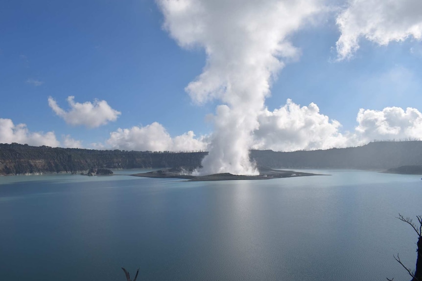 Smoke is seen coming out of Manaro volcano in the middle of a body of water.