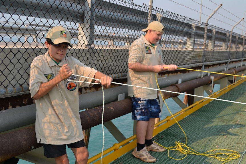 Two Broome High School students pulling up water samples from Broome jetty to take measurements for the CSIRO's app Eye on Water