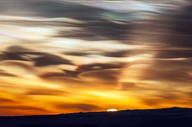 Beautiful wisps of stratospheric clouds over Antarctica with the sun on the horizon