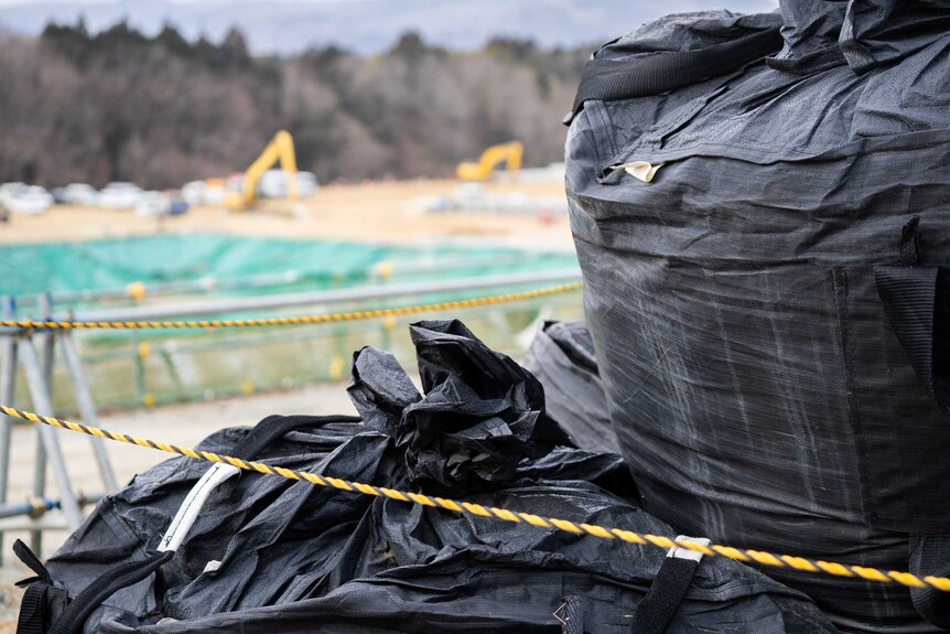 A big pile of black plastic bags roped off in a field