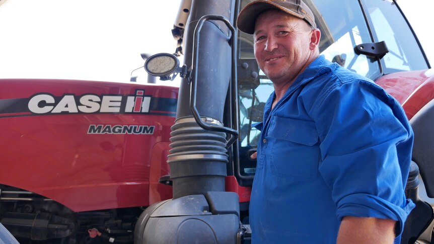 Esperance farmer smiles at the camera as he climbs into his tractor.