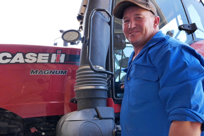 Esperance farmer smiles at the camera as he climbs into his tractor.