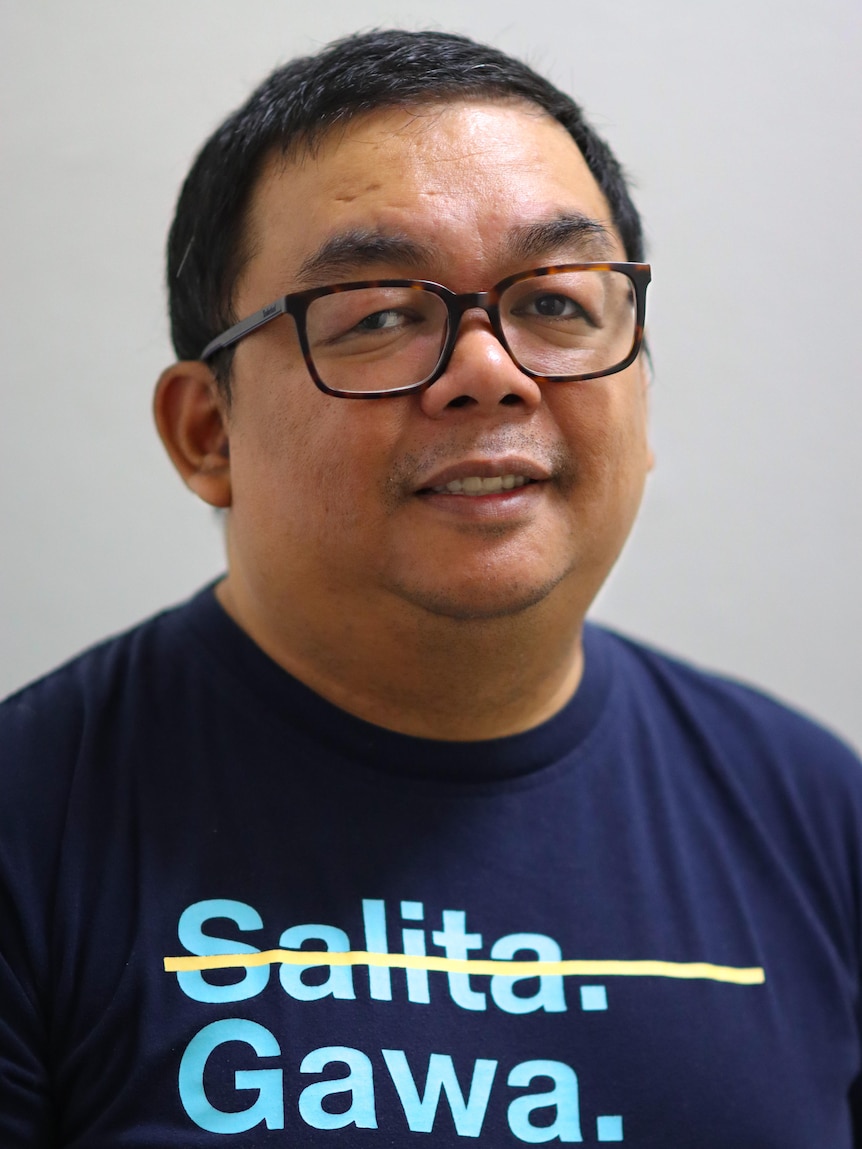 A man in glasses and a tee shirt looks at the camera. 