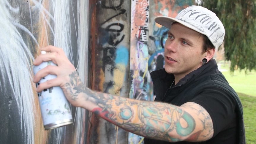 Tasmanian artist James Cowan spray painting a mural.