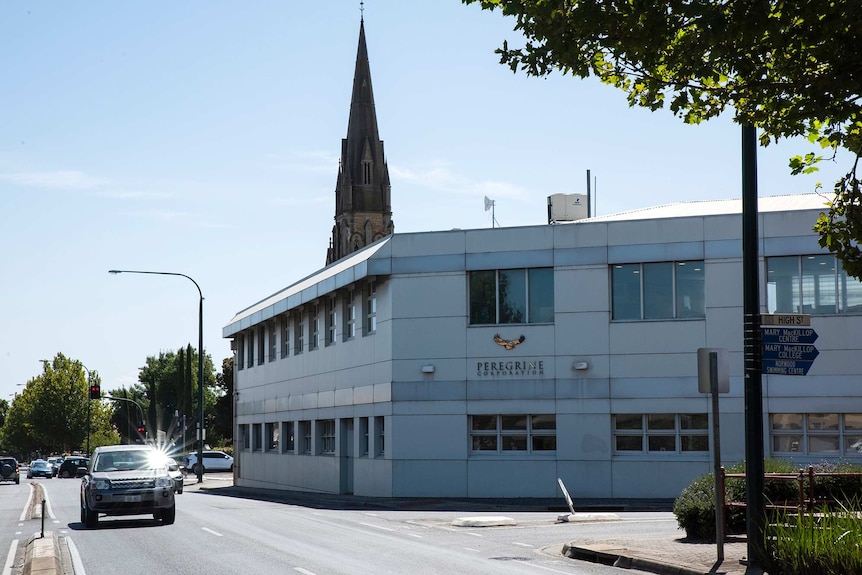 An image of a building's two-story facade with a church spire in the background.