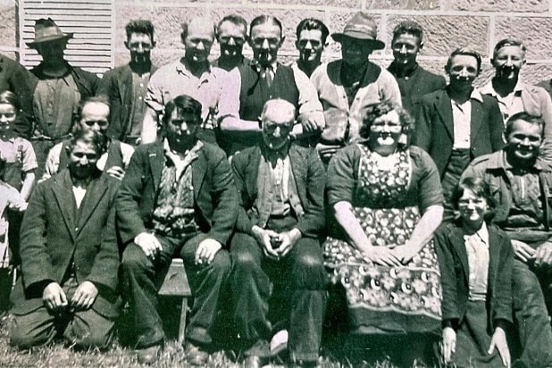 A black and white photo of a group of men and woman standing and sitting in rows.