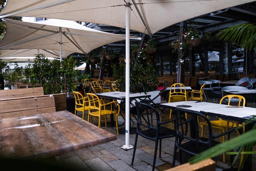 an empty outdoor area of a bar with empty tables and chairs