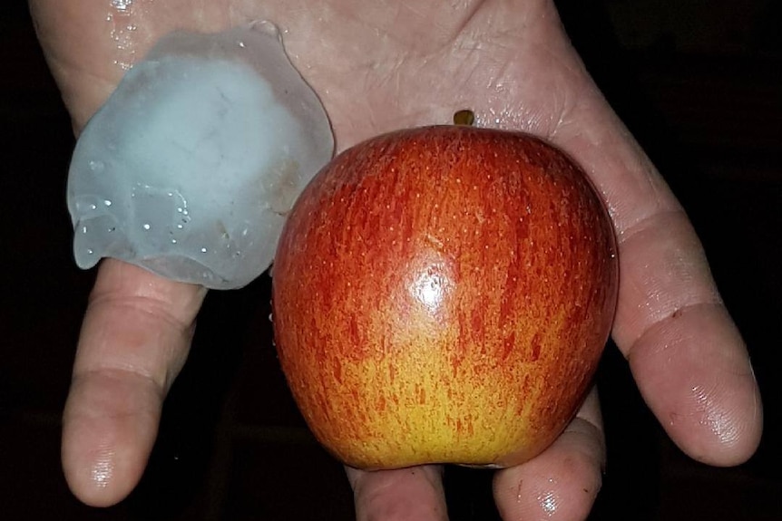 A large chunk of ice, next to an apple.