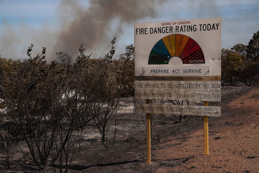 A fire danger rating sign next to scorched bushland.