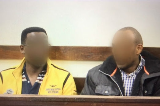 Two men sit together in court.