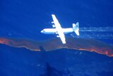 A Hercules aircraft drops dispersant on the oil spill.