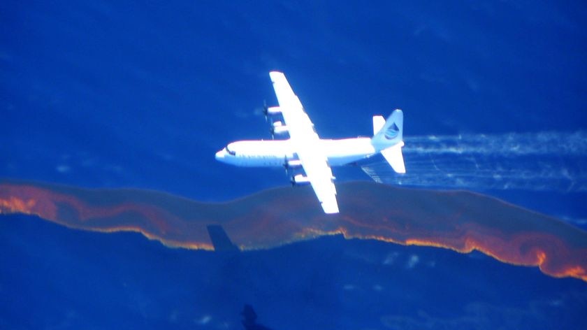 A Hercules aircraft drops dispersant on the oil spill.