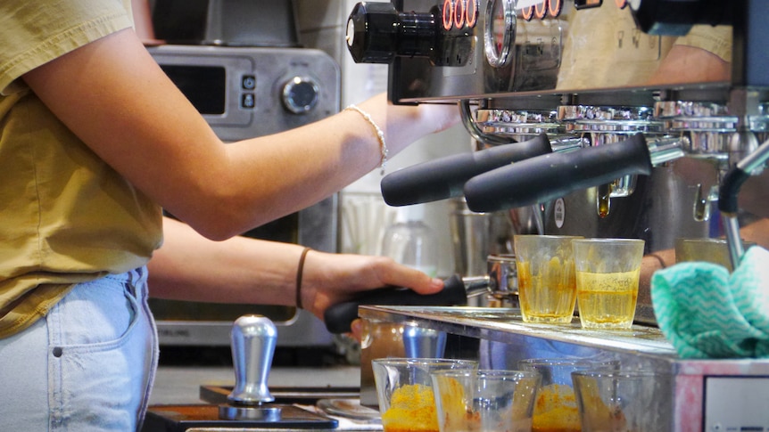 A barista makes a coffee on a machine at a cafe 