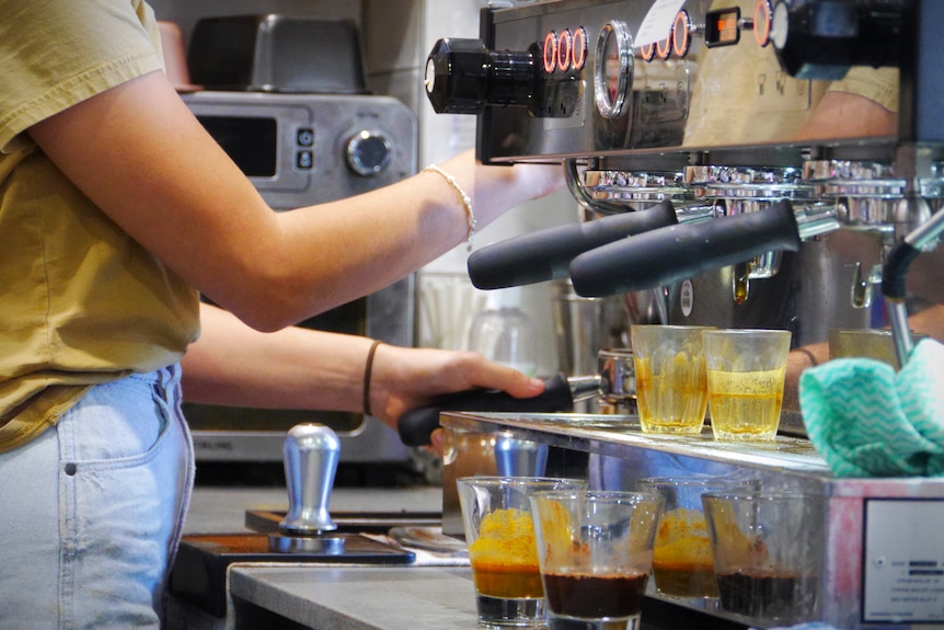 A barista makes a coffee on a machine at a cafe 