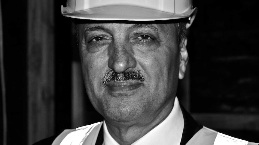 A black and white portrait of Hobart property developer Ali Sultan wearing a hard hat