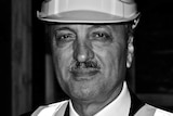 A black and white portrait of Hobart property developer Ali Sultan wearing a hard hat