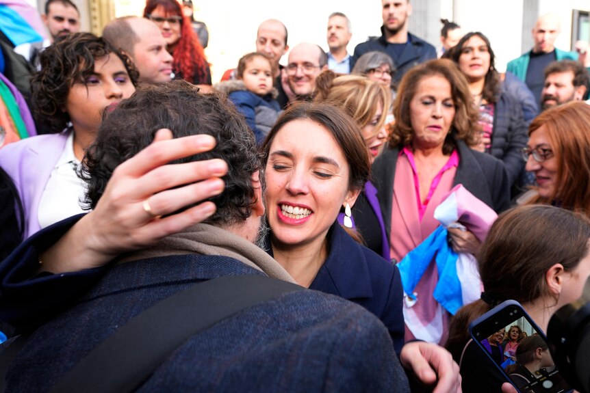 A woman  hugging a person surrounded by a crowd of people
