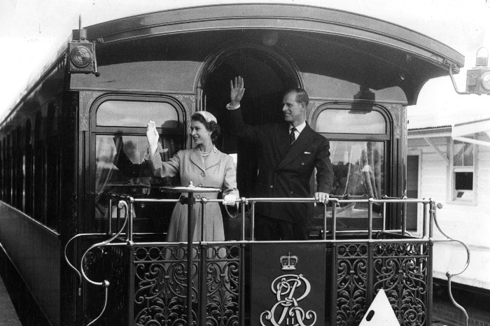 Queen Elizabeth II and the Duke of Edinburgh wave from a train.