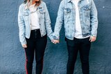 A couple wearing denim jackets holding hands