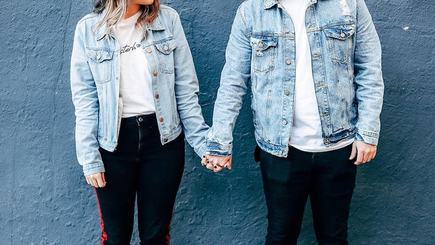 A couple wearing denim jackets holding hands