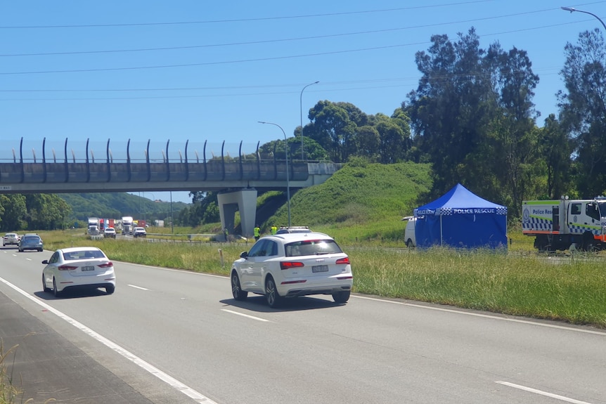 Cars travel on a highway near a blue police tent