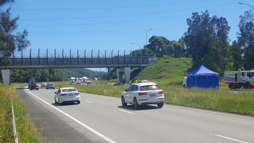 Cars travel on a highway near a blue police tent