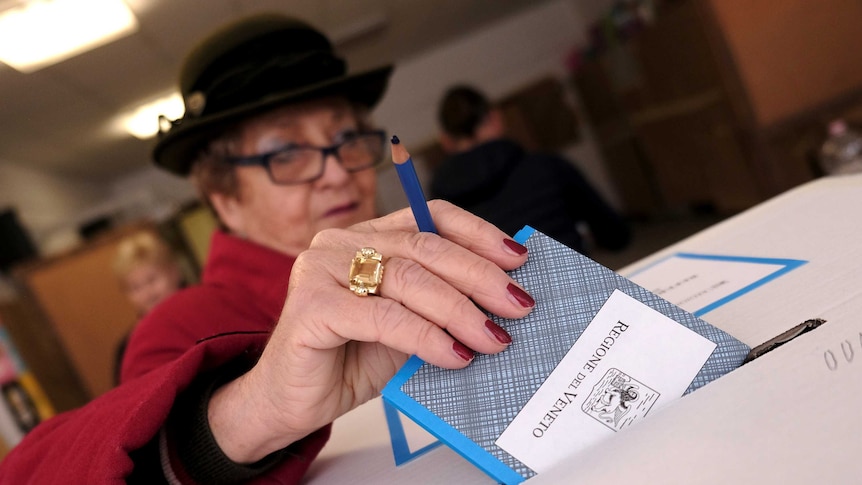 A woman casts her vote for Veneto's autonomy referendum at a polling station in Venice, Italy.