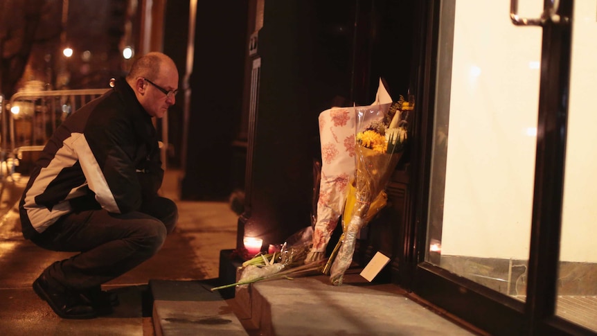 A man places flowers in memory of Philip Seymour Hoffman